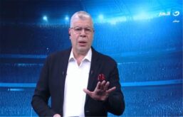 صورة لأحمد شوبير يتحدث بحماس، مع خلفية لملعب استاد القاهرة الدولي.