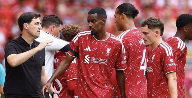 لاعب كرة قدم يرتدي قميص ليفربول يقف في الملعب